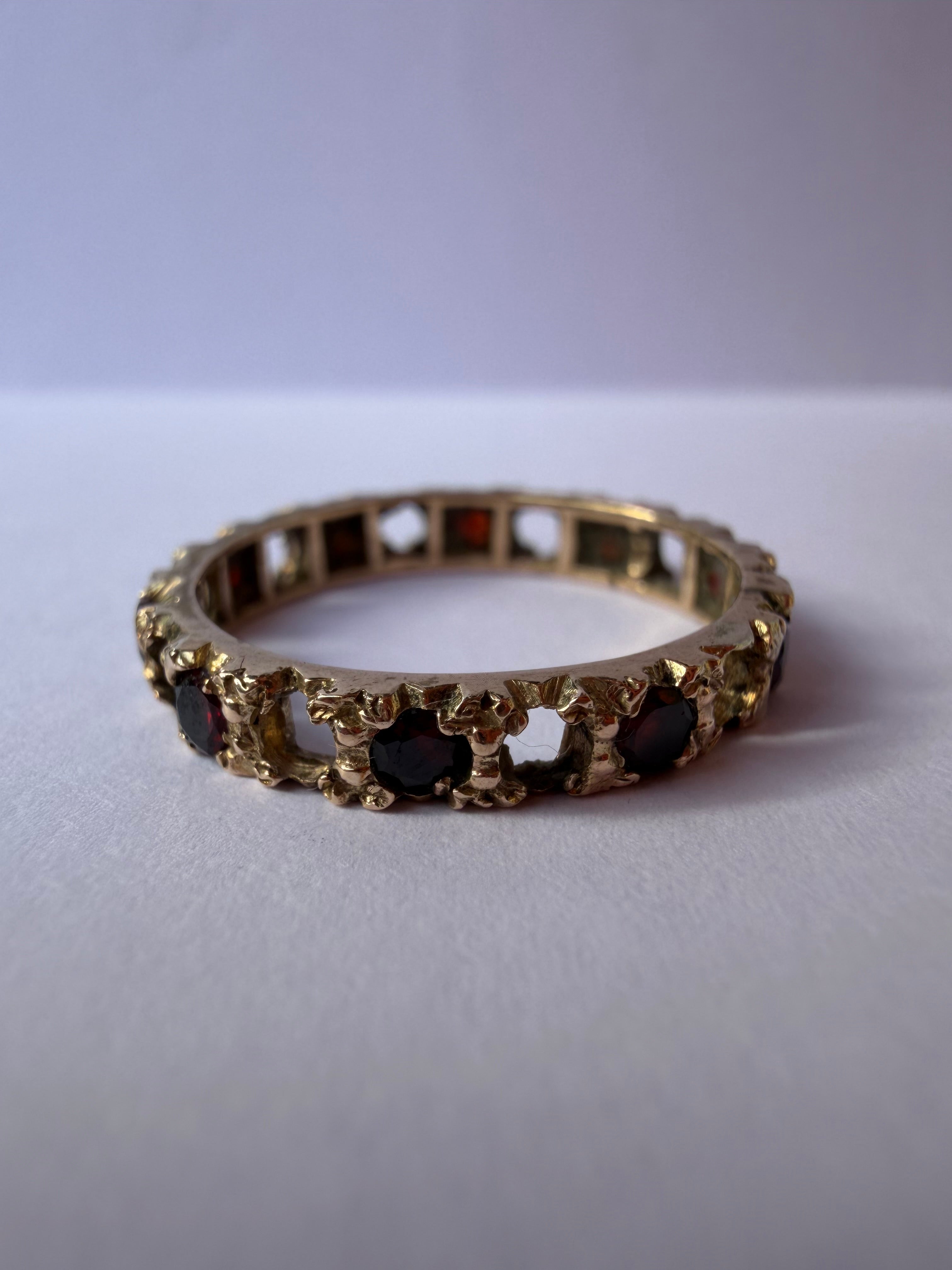 Lot 28: 9ct gold eternity ring with garnet